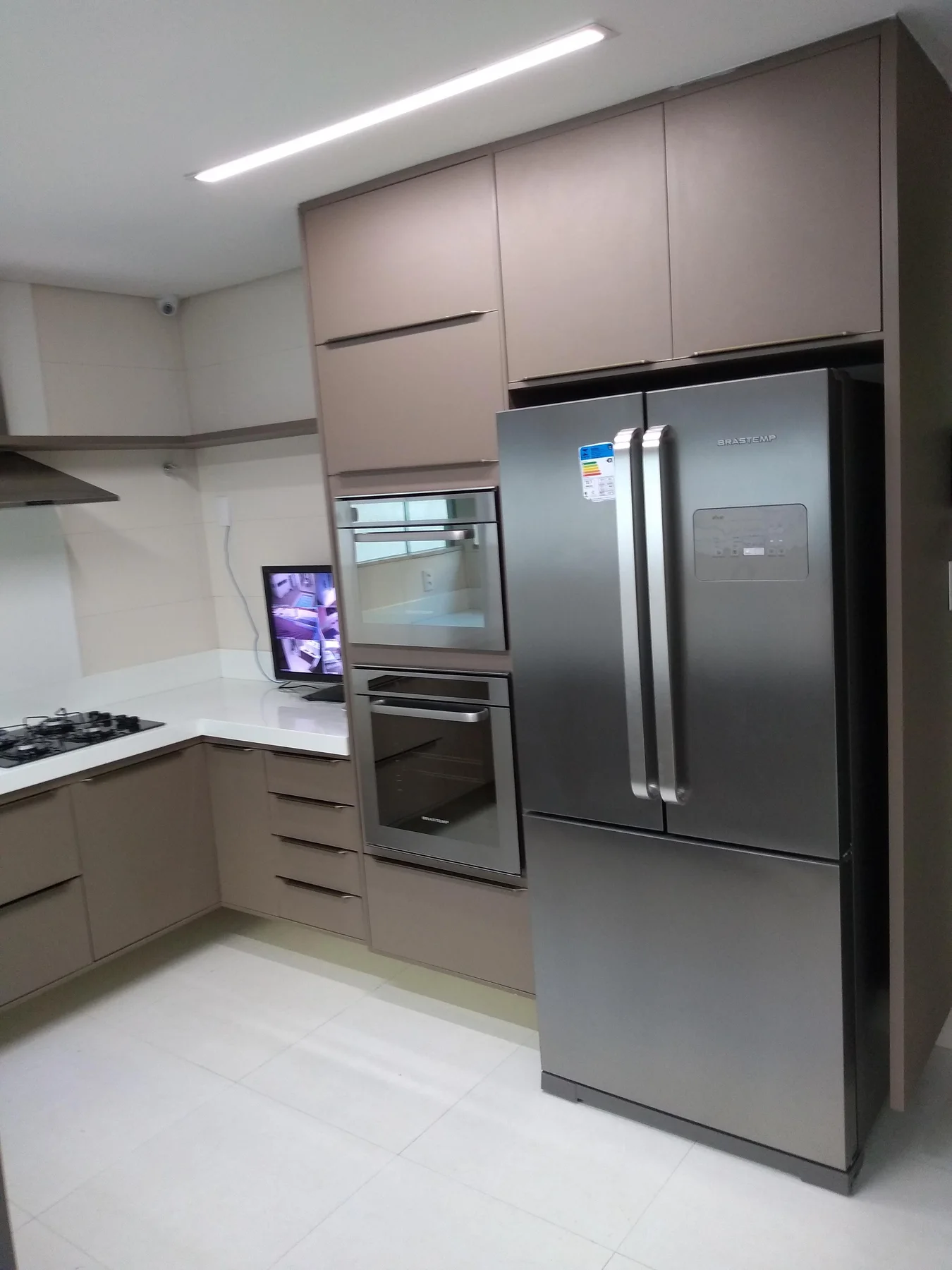 Cozinha clara com marcenaria superior e geladeira