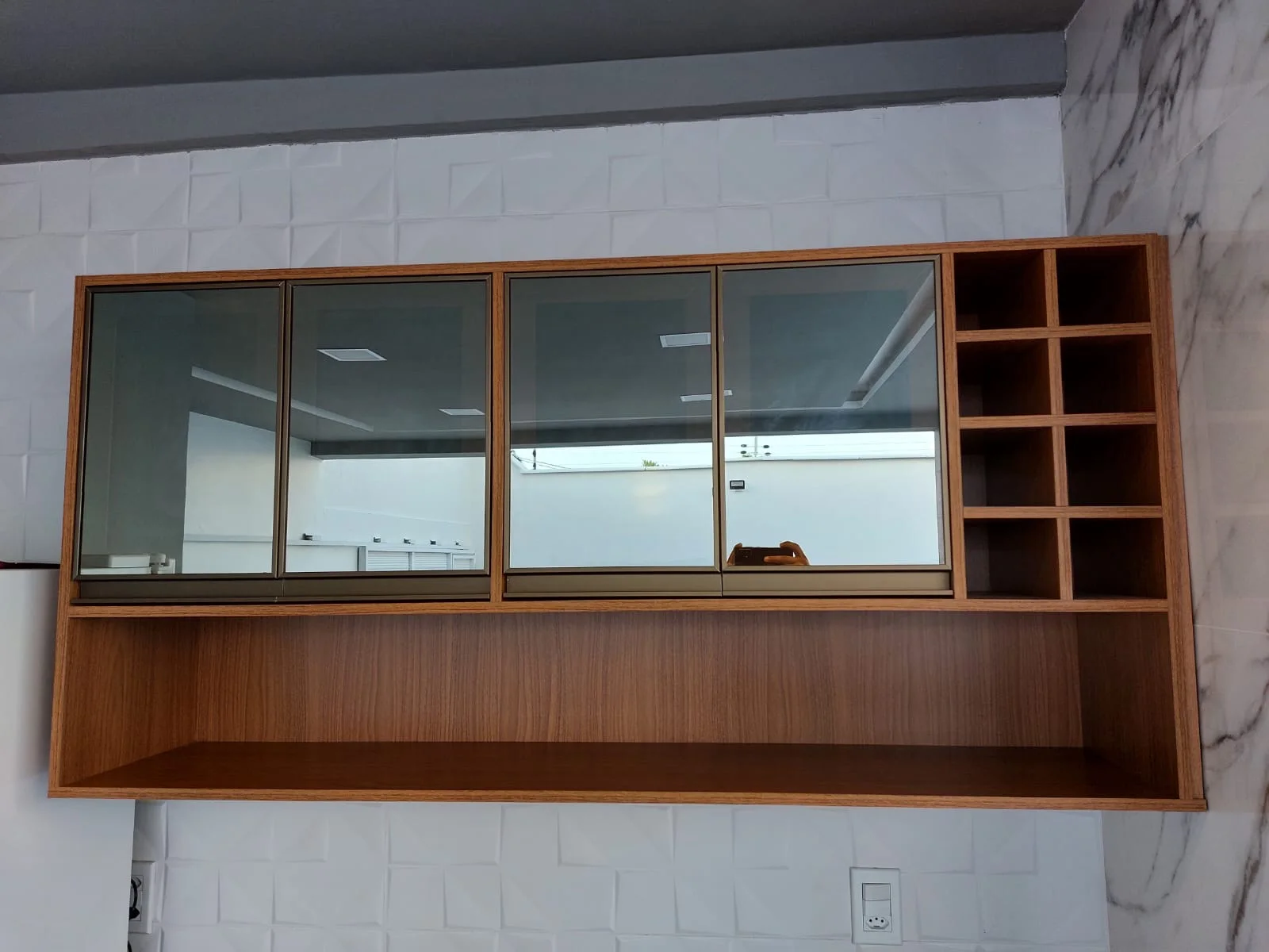 Painel suspenso em madeira com nichos e portas de vidro